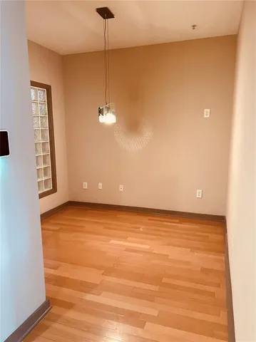 a view of an empty room with window and chandelier fan