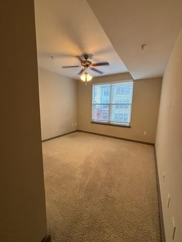 an empty room with windows and chandelier fan