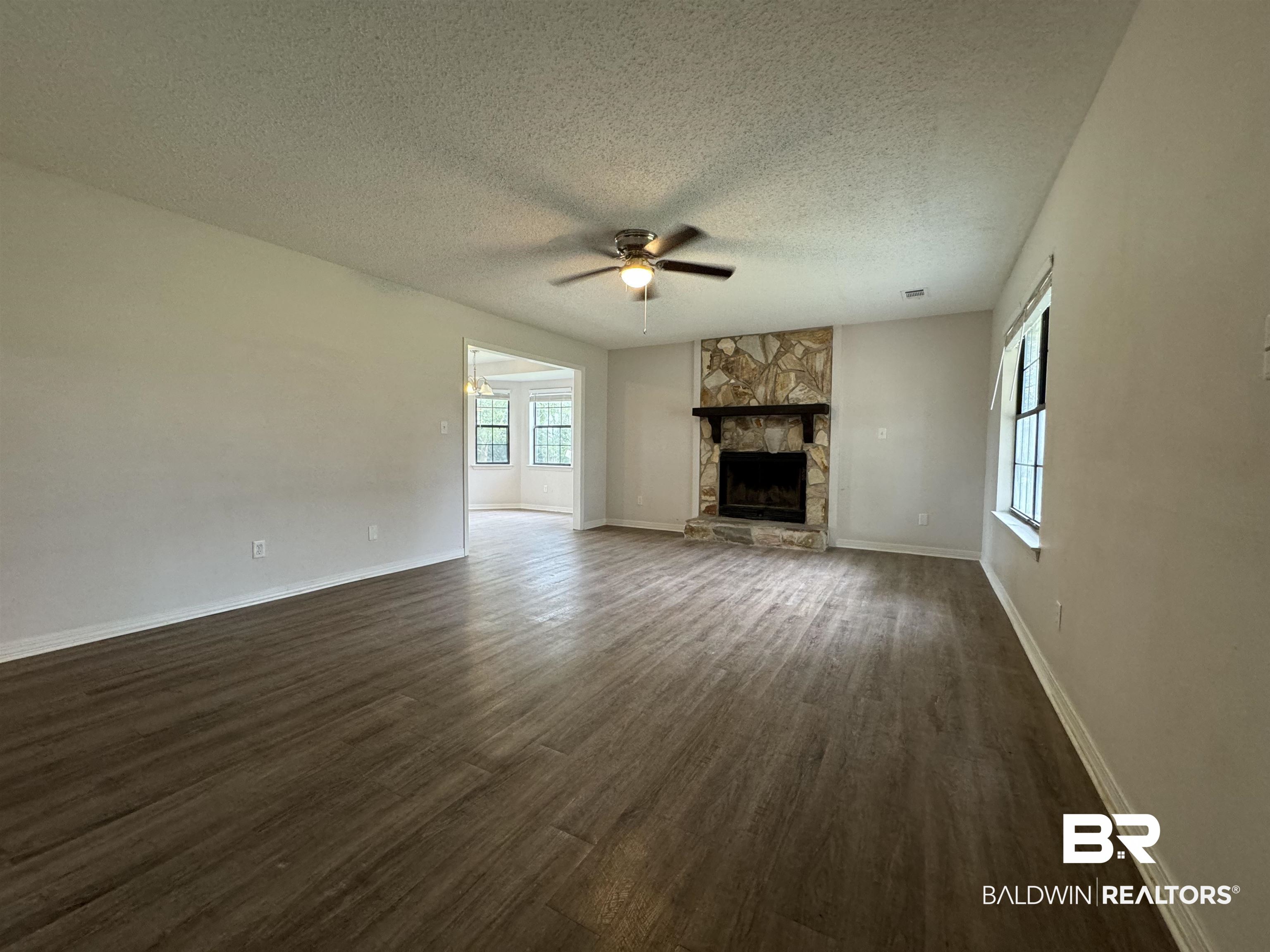 70 Plum Street Uriah, AL 36480 - Photo 3 of 36 Unfurnished living room with a textured ceiling, a fireplace, dark hardwood / wood-style flooring, and ceiling fan