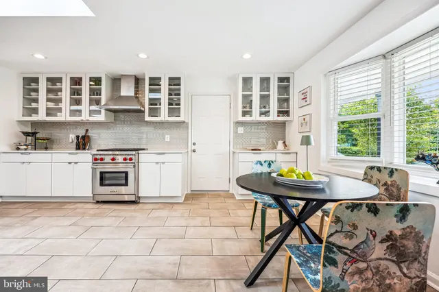 a kitchen with stainless steel appliances kitchen island granite countertop a table chairs in it and wooden floors