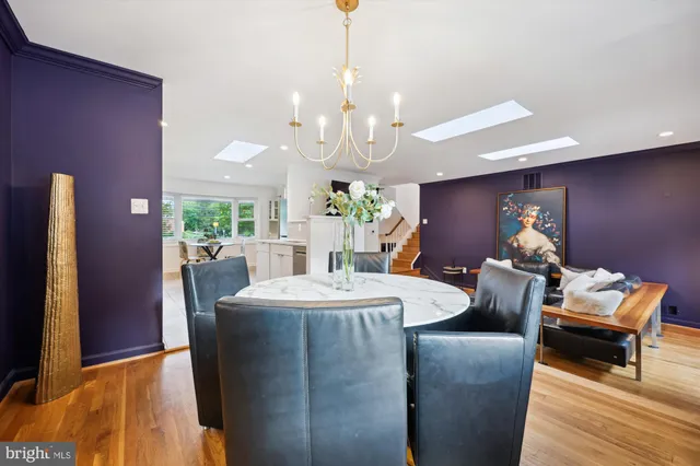 a dining room with chandelier and wooden floor
