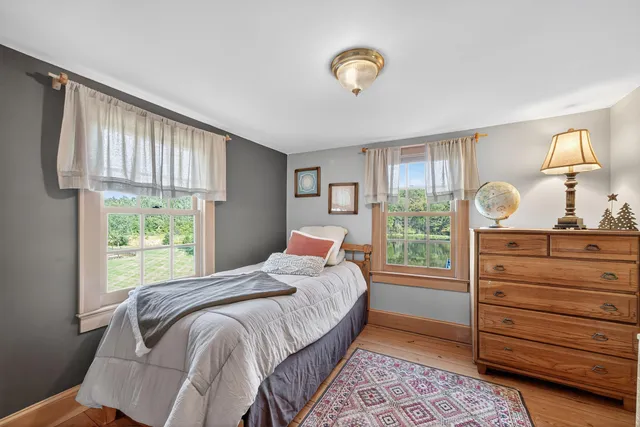 a bedroom with a bed and a dresser next to a window
