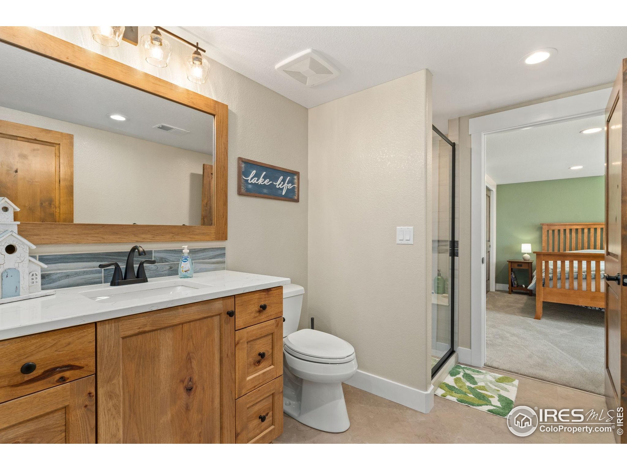 3324 Fox Crossing Place Loveland, CO 80537 - Photo 44 of 47 a bathroom with a granite countertop sink a toilet and a mirror
