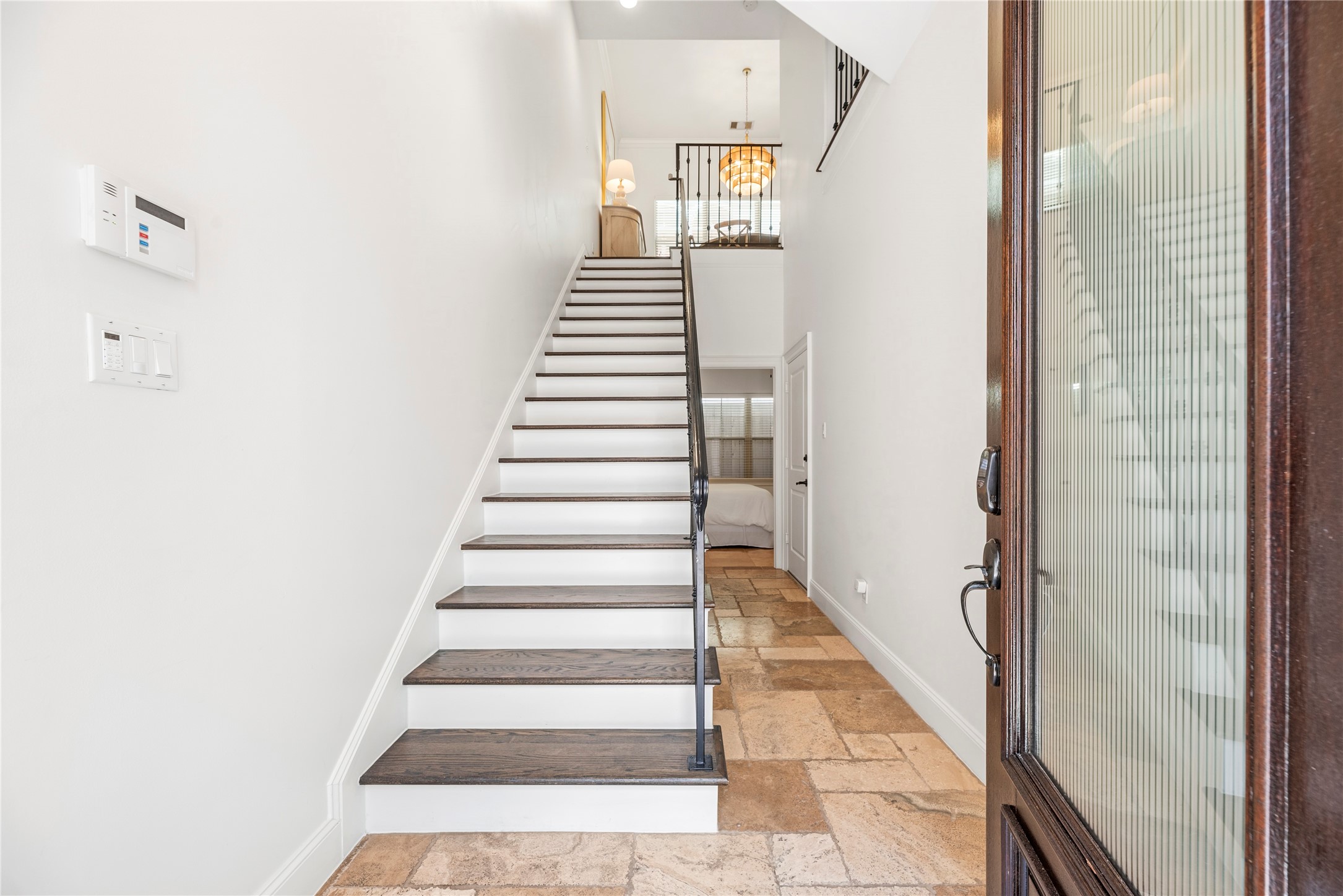 1537 Haddon Street Houston, TX 77006 - Photo 28 of 48 Foyer showcases a bright entryway with a staircase leading to an upper level. The floor features a stone tile pattern. The entry door has a glass insert, allowing natural light to fill the space. Note the first floor bedroom/study with its own en-suite bathroom. Garage entry is the door to the right side of this picture.