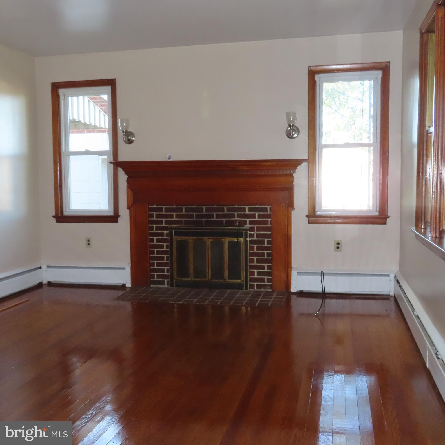 1126 Crottlestown Road Chambersburg, PA 17202 - Photo 7 of 47 an empty room with wooden floor a fireplace and windows