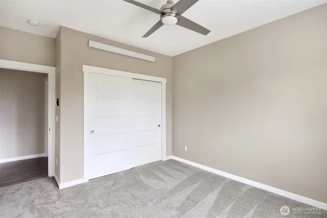 an empty room with closet and a ceiling fan