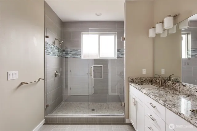 a bathroom with a granite countertop sink a mirror and a shower