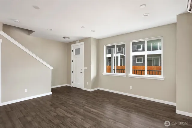 a view of an empty room with wooden floor and windows