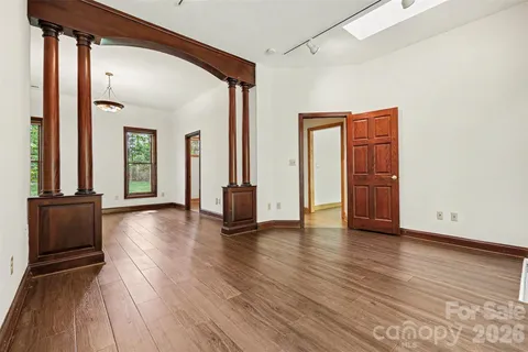 a view of an empty room with wooden floor and a window