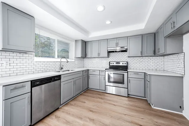 a kitchen with granite countertop a sink cabinets and stainless steel appliances