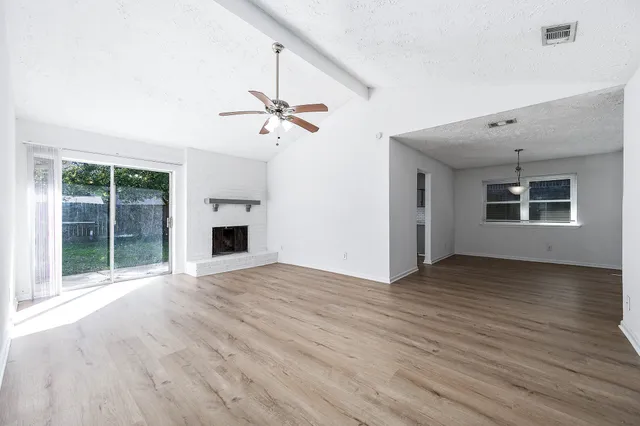 a view of an empty room with a window and wooden floor
