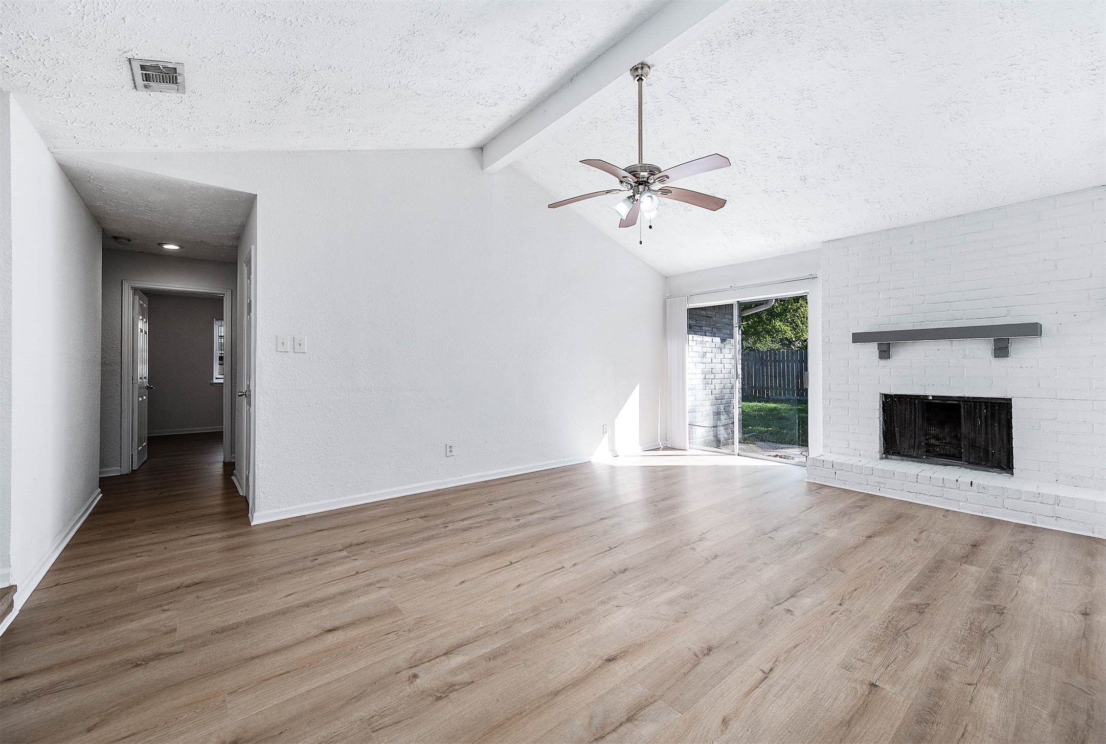 24007 Pepperrell Pl Street Katy, TX 77493 - Photo 7 of 24 an empty room with wooden floor a ceiling fan a fireplace and windows