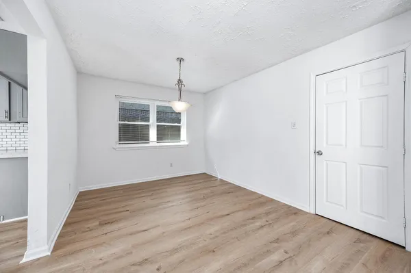 an empty room with wooden floor cabinet and windows