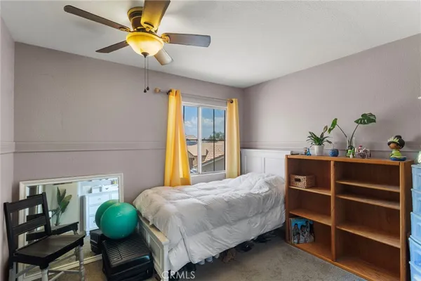 a bedroom with a bed table chair and a window