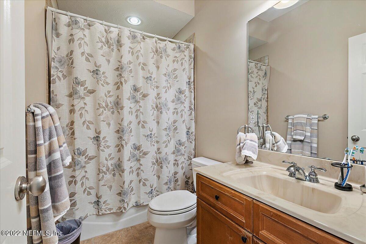 649 Treehouse Circle St. Augustine, FL 32095 - Photo 43 of 71 a bathroom with a granite countertop sink a toilet and a mirror
