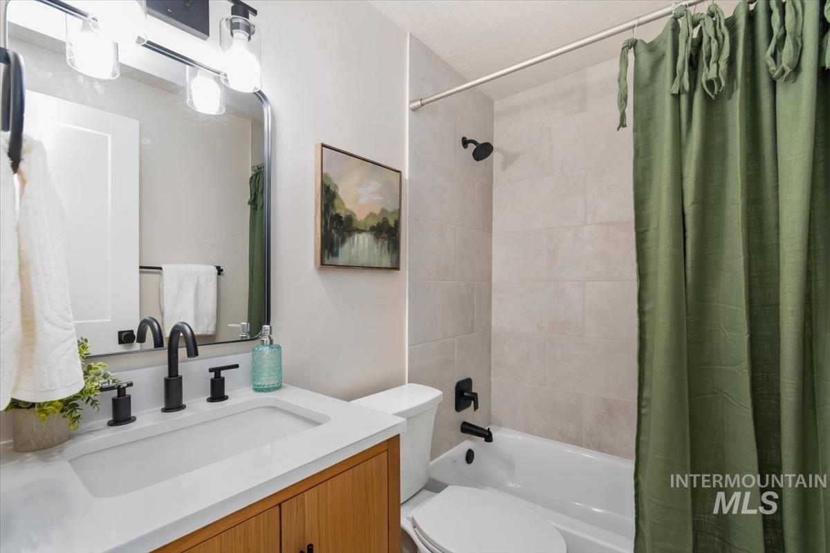 3005 West Hester Street Boise, ID 83702 - Photo 21 of 32 Bathroom featuring a wood-finish vanity with a white countertop and integrated sink, matte black faucet hardware, and a framed mirror with a three-light fixture