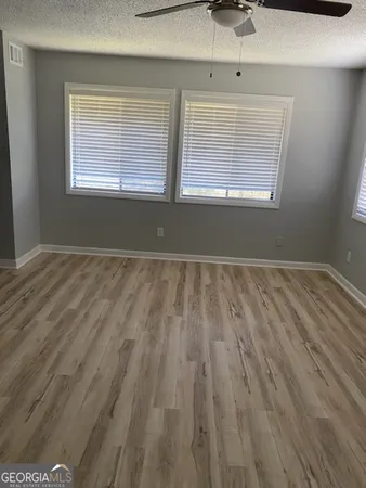 a view of empty room with wooden floor and fan