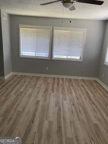 a view of empty room with wooden floor and fan