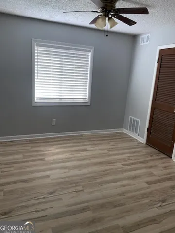 a view of empty room with wooden floor and fan