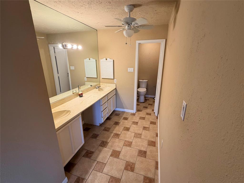 2051 Embassy Way Carrollton, TX 75006 - Photo 15 of 20 a bathroom with a sink a toilet a mirror and shower
