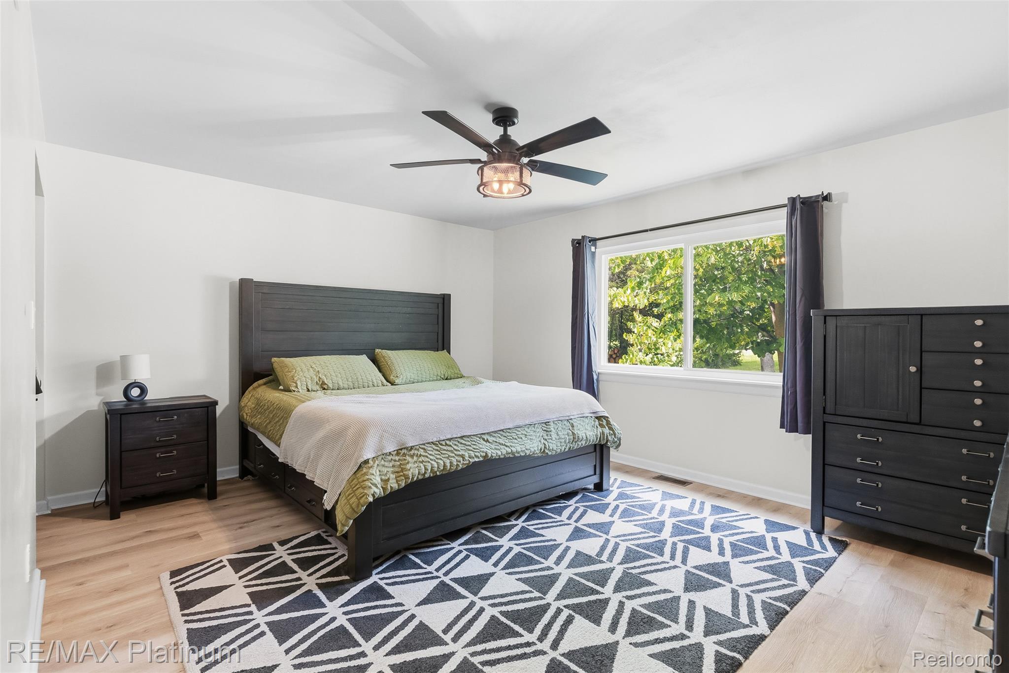 8370 West Rolston Road Linden, MI 48451 - Photo 20 of 36 Spacious room featuring light wood-finish flooring, a large window with dark drapes, and a ceiling fan with integrated lighting