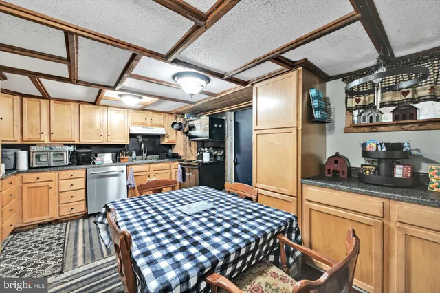 a kitchen with stainless steel appliances granite countertop a refrigerator a sink dishwasher a stove and white cabinets with wooden floor