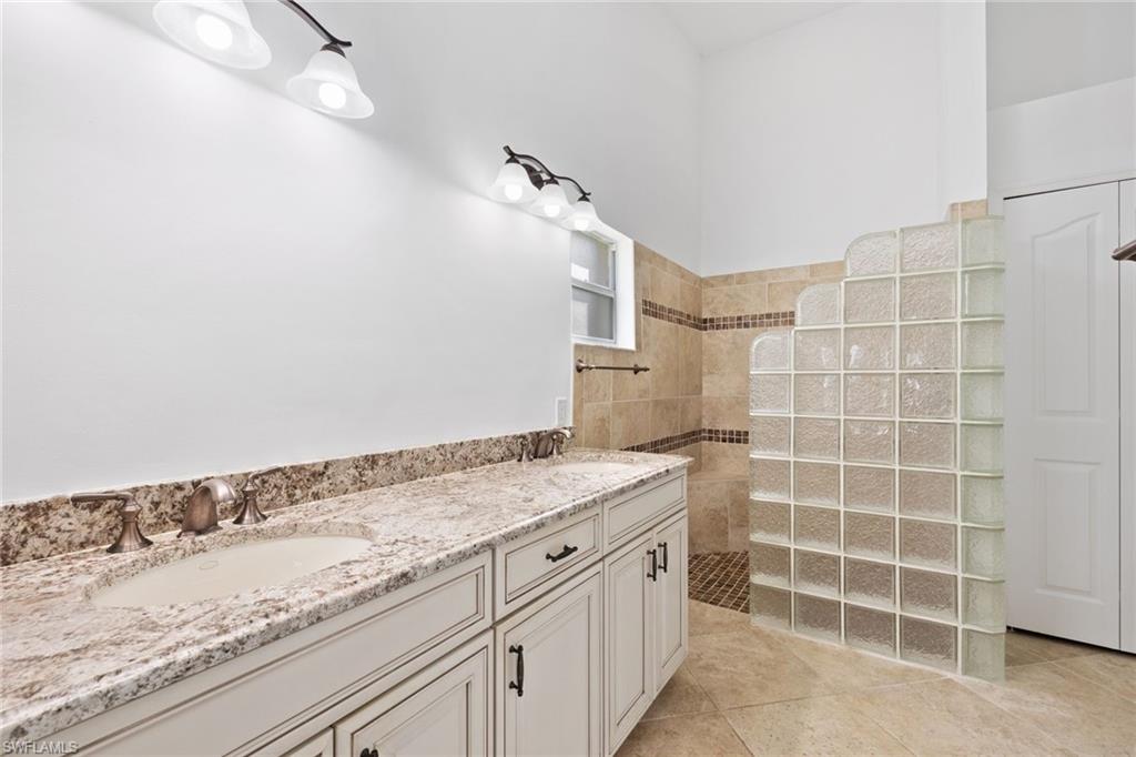 8526 Mustang Drive Naples, FL 34113 - Photo 12 of 24 Bathroom featuring tile patterned floors, walk in shower, double vanity, and a sink