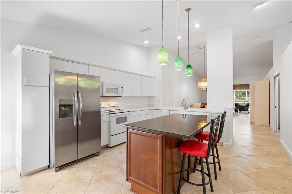 8526 Mustang Drive Naples, FL 34113 - Photo 3 of 24 Kitchen featuring white appliances, a high ceiling, light tile patterned flooring, and a center island