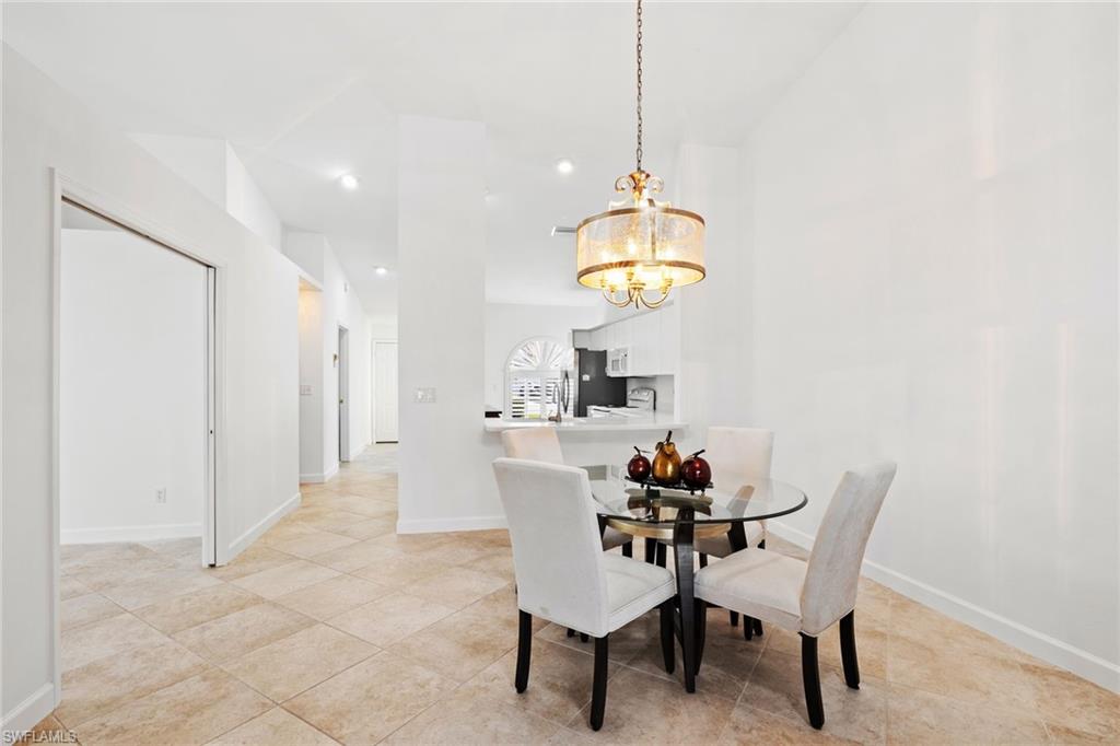 8526 Mustang Drive Naples, FL 34113 - Photo 5 of 24 Dining area featuring baseboards, light tile patterned flooring, recessed lighting, vaulted ceiling, and a chandelier