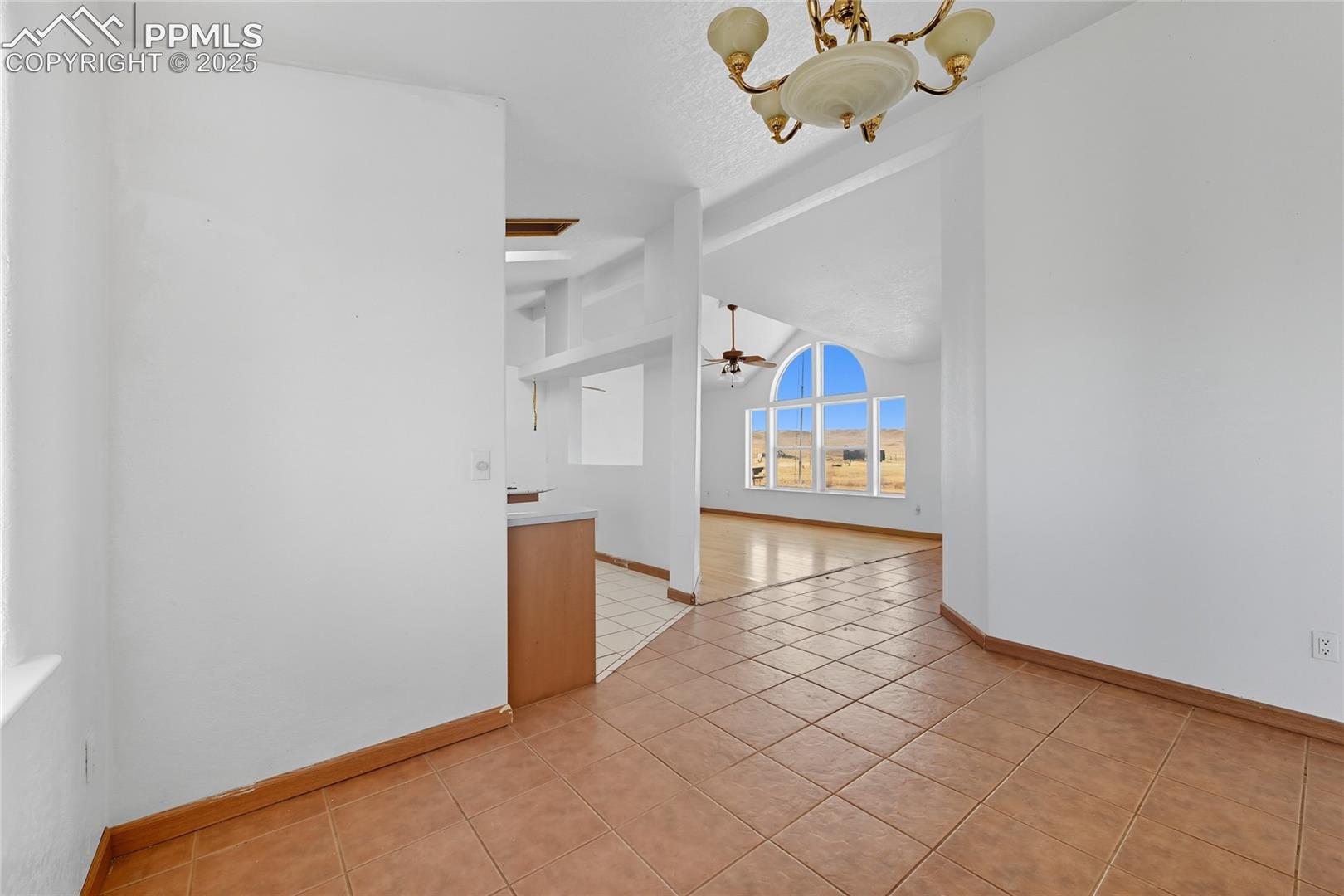 16595 North Yoder Road Calhan, CO 80808 - Photo 15 of 28 Empty room featuring light tile patterned floors, a chandelier, and a ceiling fan