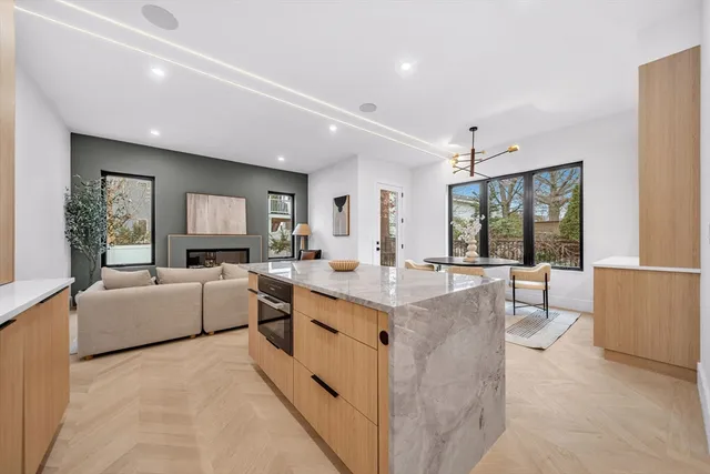 a large white kitchen with a stove a sink dishwasher and a refrigerator with wooden floor