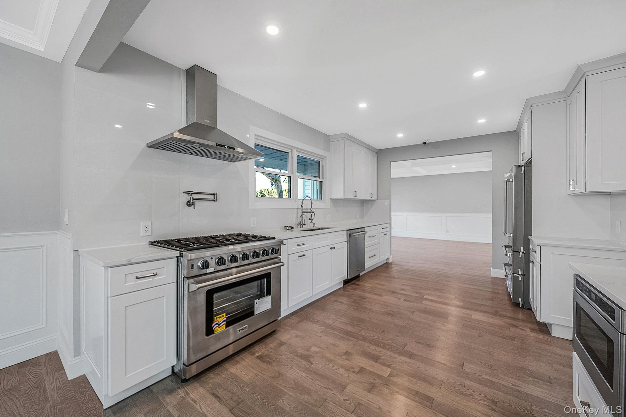 141 Wilmot Road Scarsdale, NY 10583 - Photo 14 of 49 Kitchen featuring a decorative wall, wainscoting, high end appliances, exhaust hood, and white cabinetry