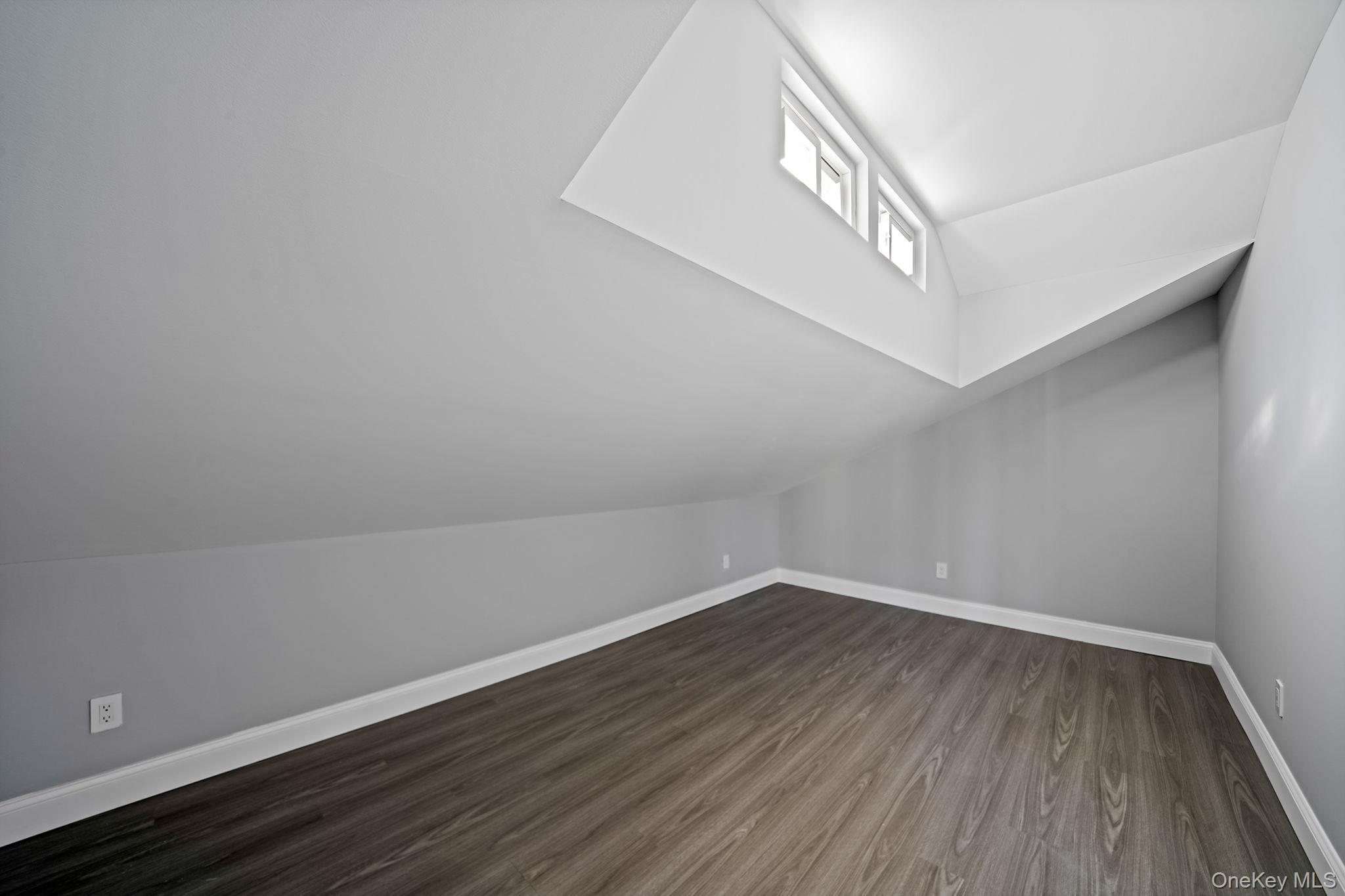 141 Wilmot Road Scarsdale, NY 10583 - Photo 23 of 49 Additional living space featuring dark wood-style floors and vaulted ceiling