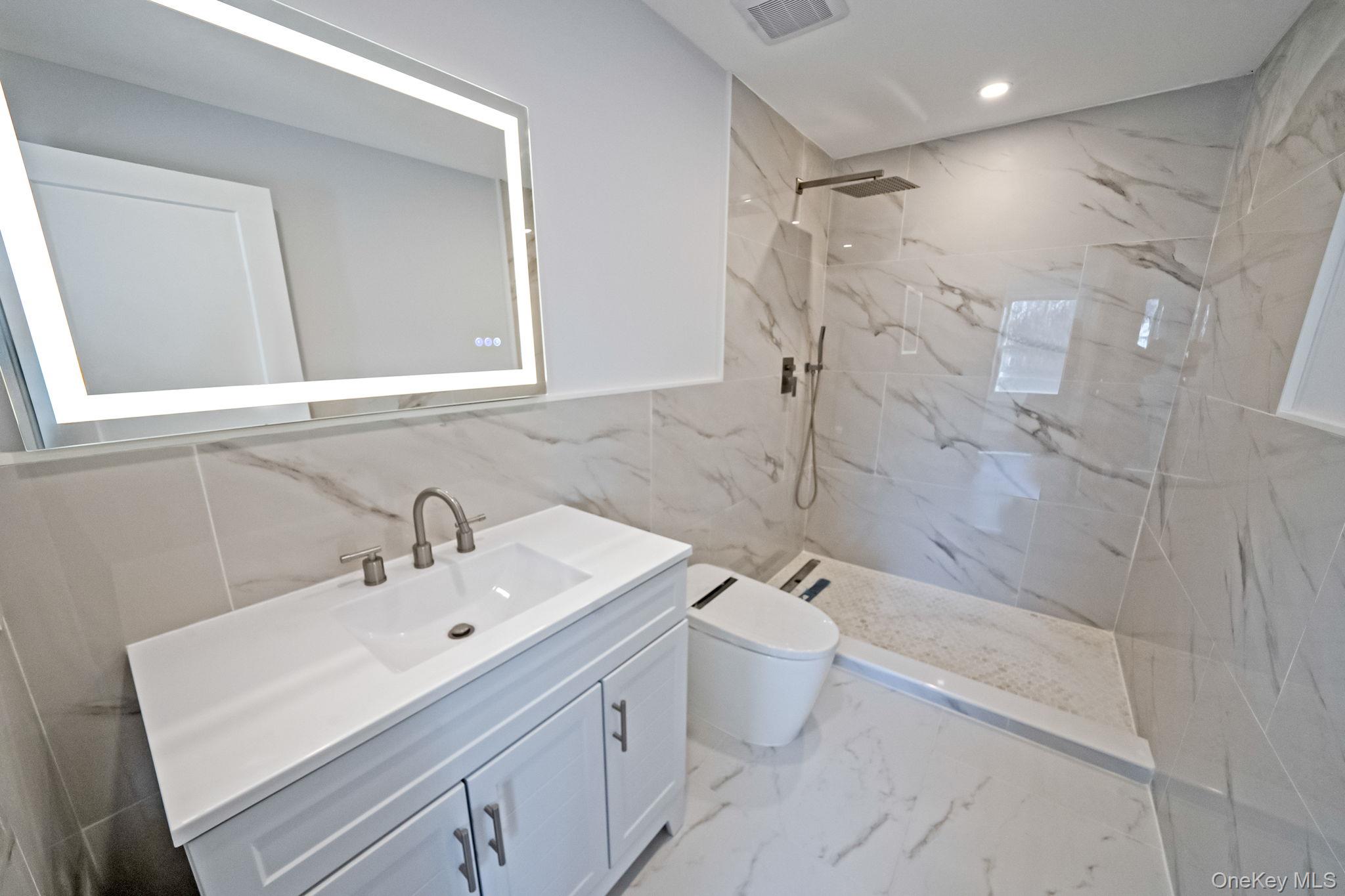 141 Wilmot Road Scarsdale, NY 10583 - Photo 34 of 49 Full bathroom featuring vanity, tile walls, a marble finish shower, light marble finish flooring, and recessed lighting