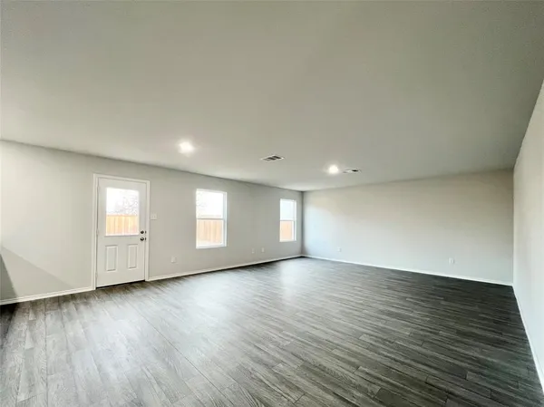 a view of an empty room with wooden floor and windows