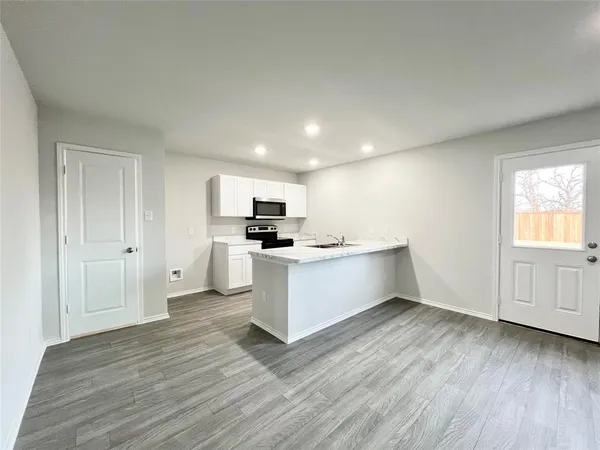 a kitchen with cabinets wooden floor and stainless steel appliances