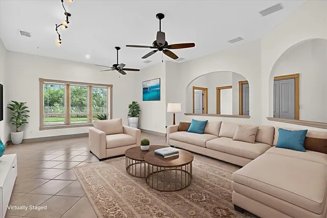 a living room with furniture a chandelier fan and a window