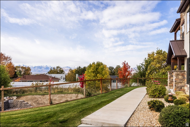 252 East Sandy Sage Way Sandy, UT 84070 - Photo 3 of 36 Stone veneer exterior, covered entry with metal roof, concrete pathway, gravel landscaping, and wood-frame fencing