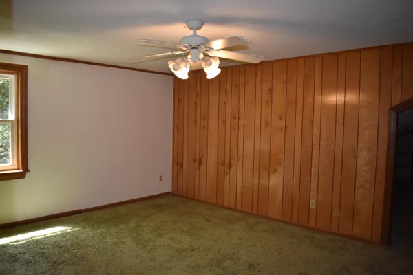 an empty room with windows and chandelier fan