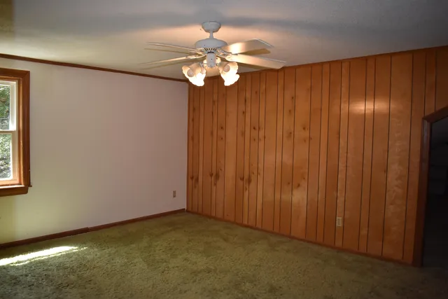 an empty room with windows and chandelier fan