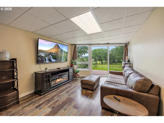 a living room with furniture a flat screen tv and floor to ceiling window
