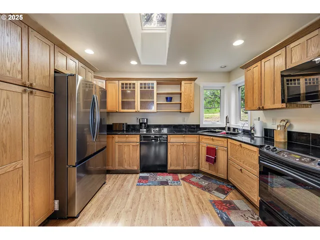 a kitchen with stainless steel appliances granite countertop a refrigerator a sink dishwasher a stove with wooden cabinets and floor