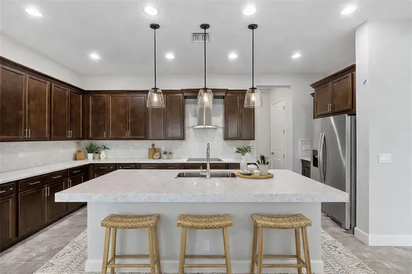 a kitchen with kitchen island a refrigerator a sink and chairs