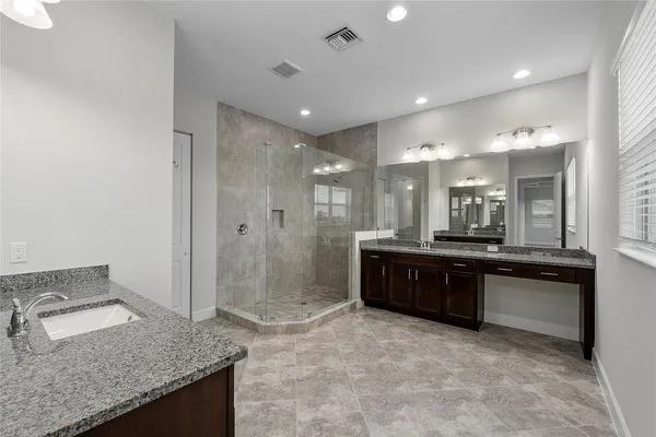 a large bathroom with a granite countertop sink a toilet a mirror and shower