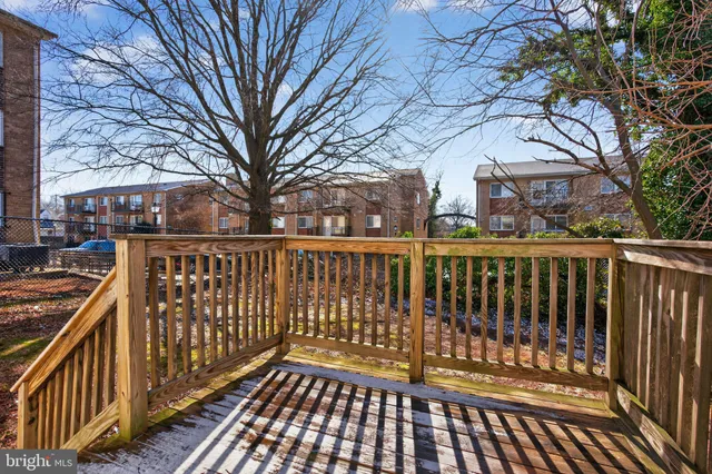 a view of a roof deck with wooden fence and large trees