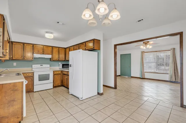 a kitchen with a refrigerator a stove top oven and cabinets