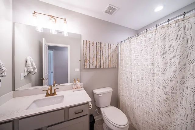 a bathroom with a sink a toilet a mirror and shower curtain