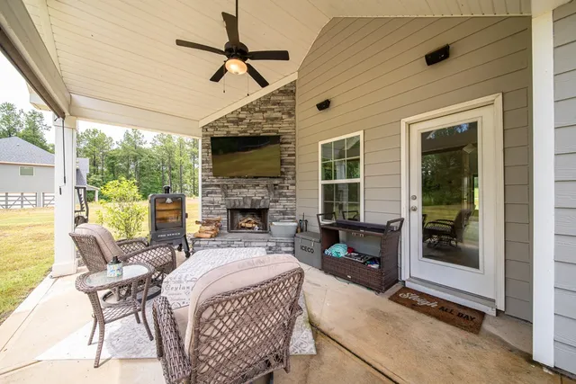 a living room with furniture a fireplace a flat screen tv and a large window