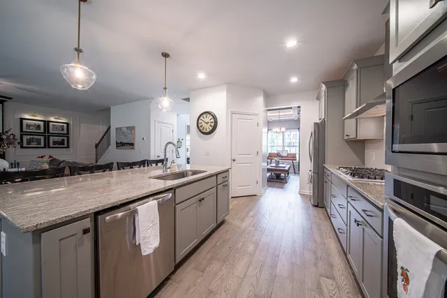 a large kitchen with stainless steel appliances granite countertop a lot of counter space and wooden floors