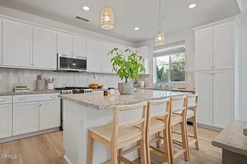 a kitchen with stainless steel appliances granite countertop white cabinets a sink and a stove